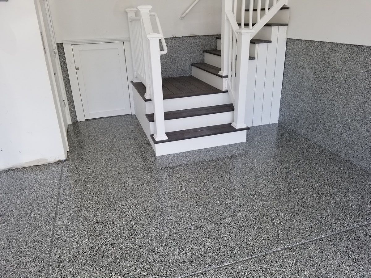 A staircase in a garage with a gray floor.