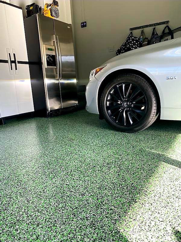 A car is parked in a garage with a green floor.
