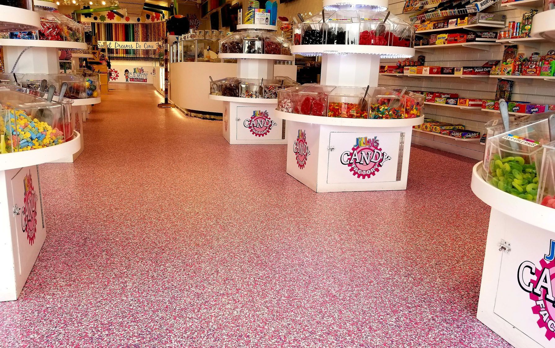 A candy store with a pink floor and shelves filled with candy.