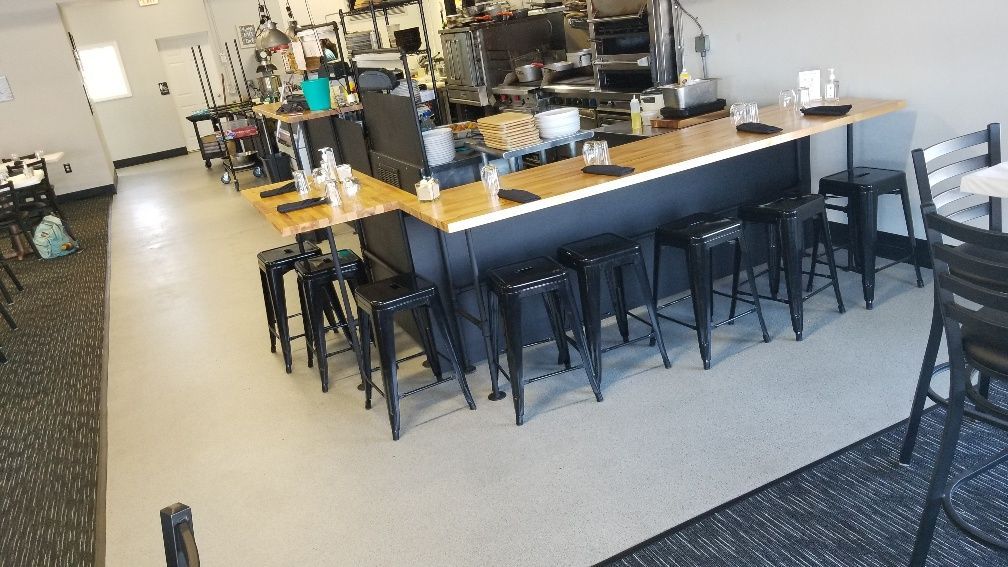 A restaurant with tables and stools and a long counter.