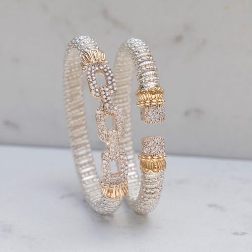 a pair of silver and gold bracelets are sitting on a table