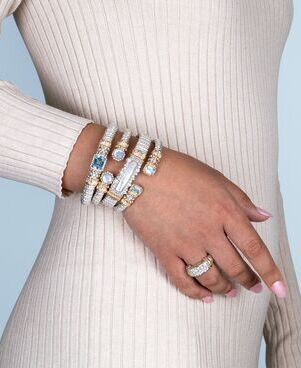 a woman is wearing a stack of bracelets and a ring on her wrist