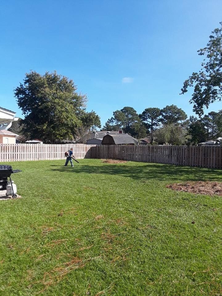 A man is mowing the grass in the backyard of a house.