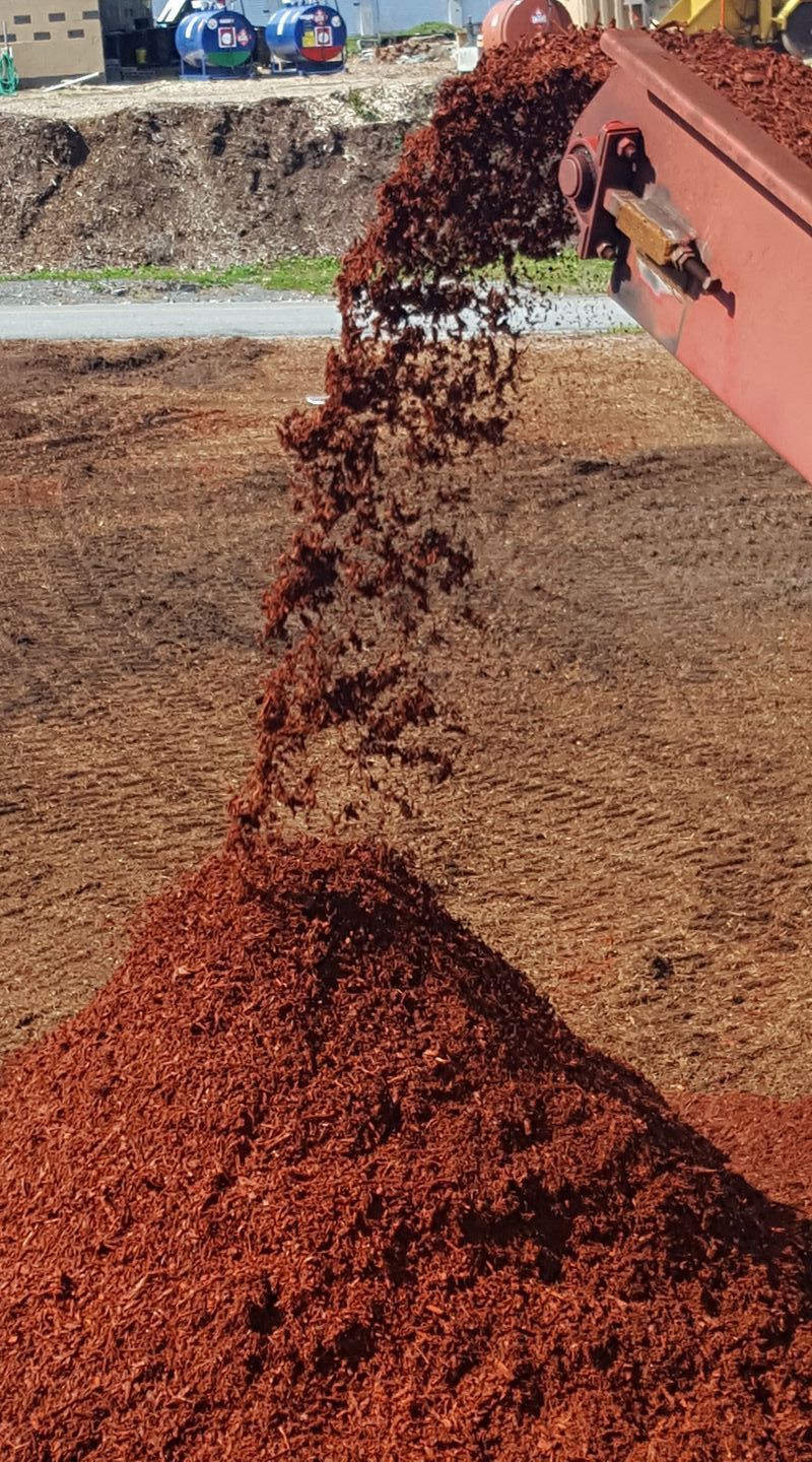 A pile of dirt is being poured from a machine into a pile of dirt.