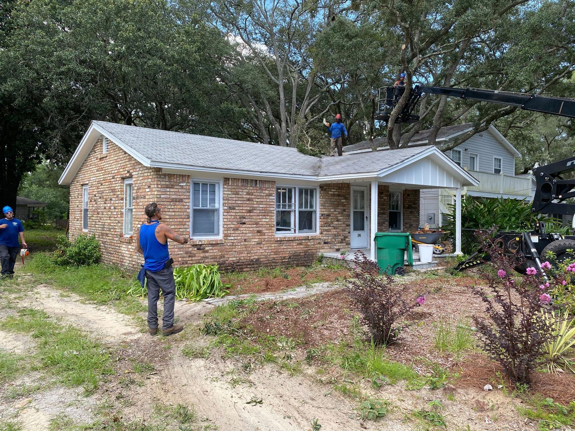 A man in a blue shirt is standing in front of a brick house.