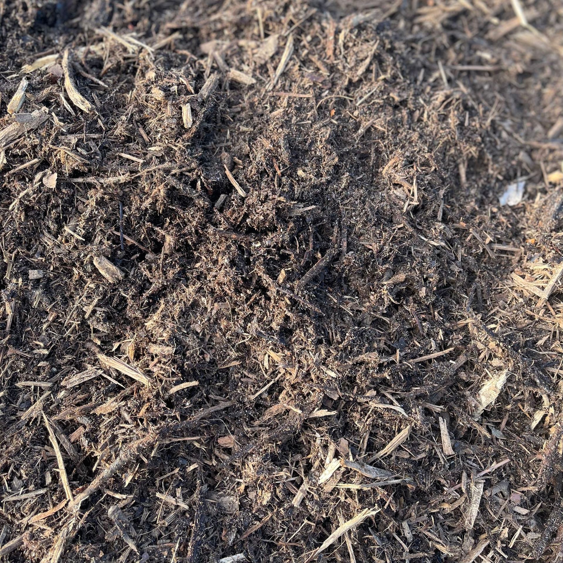 A pile of brown mulch is sitting on the ground.