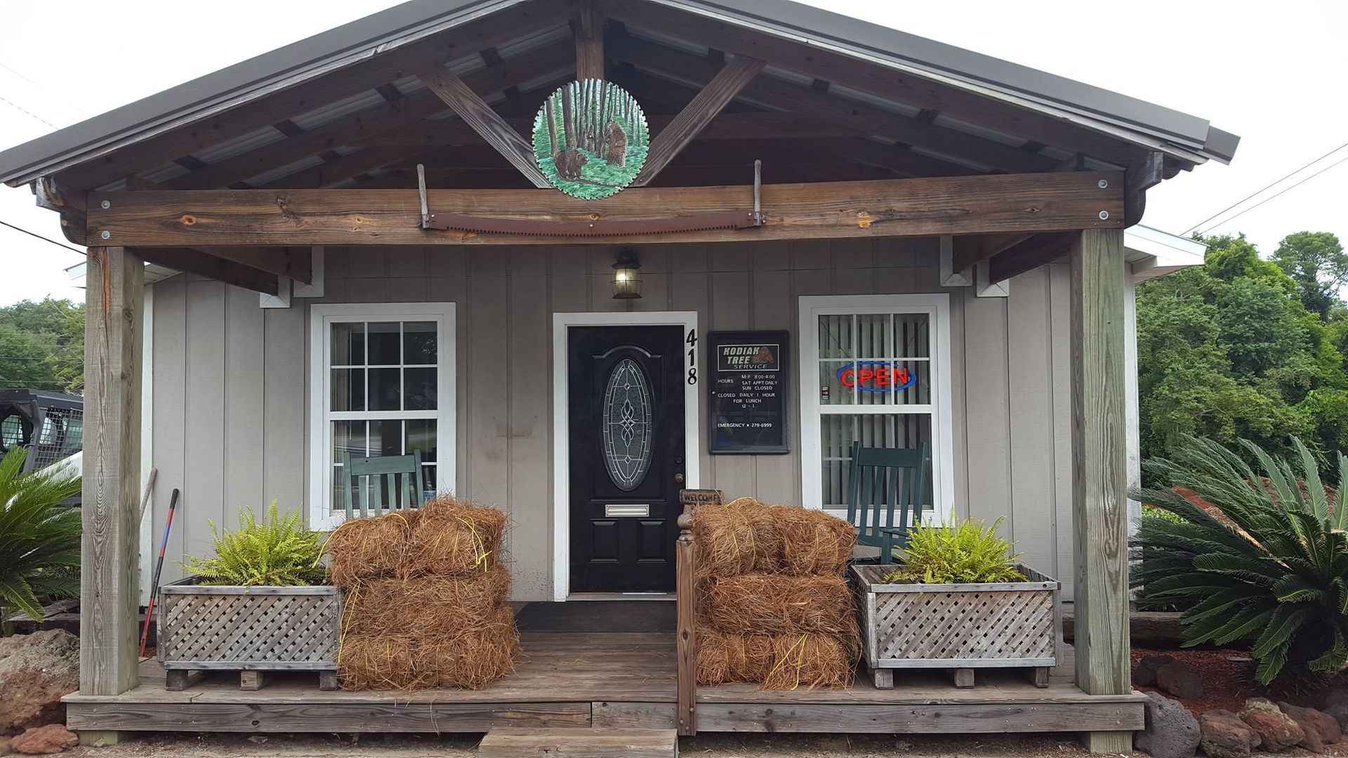 A small house with a porch and hay bales in front of it