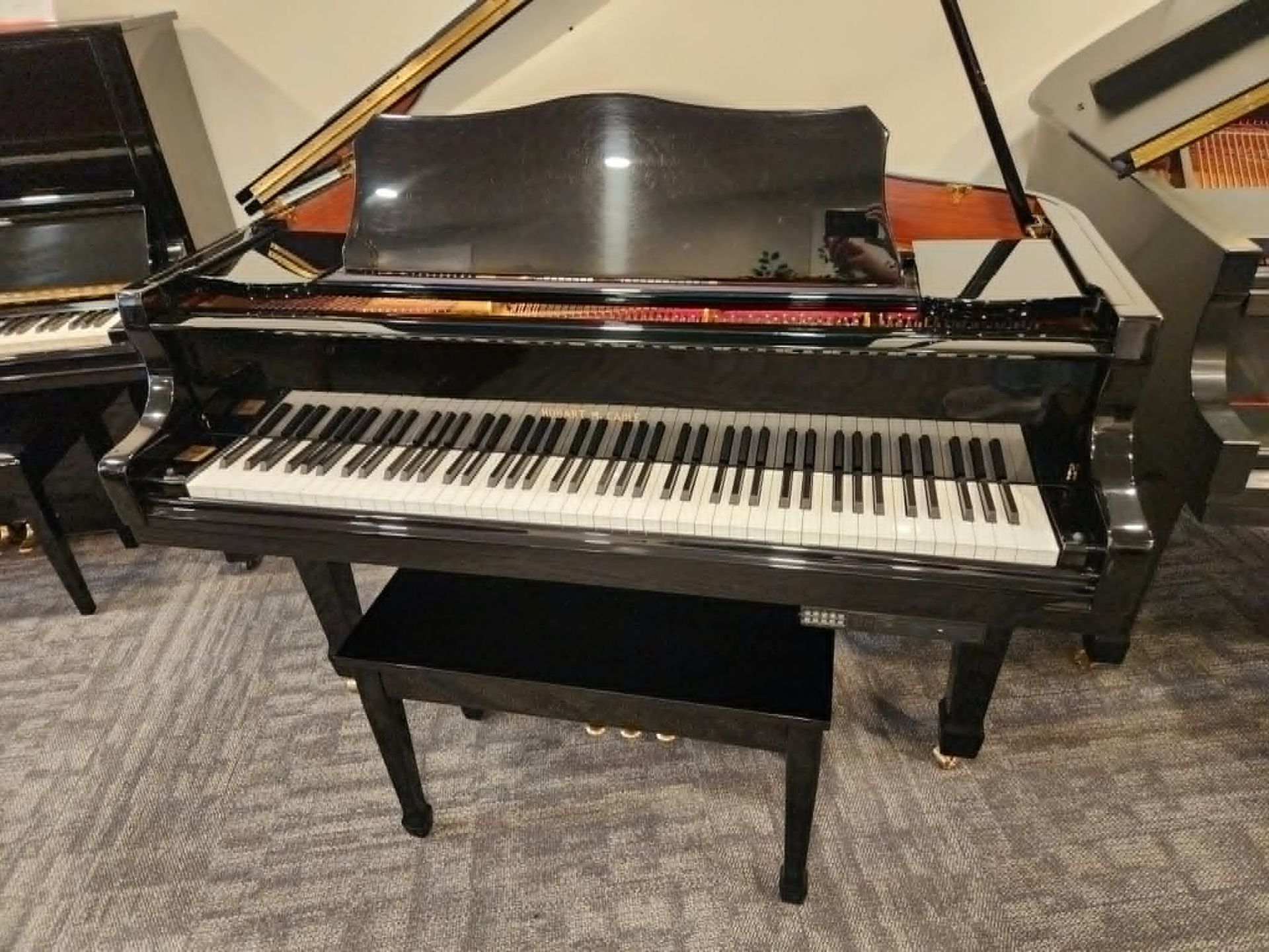 Black grand piano with matching bench in a showroom-like room