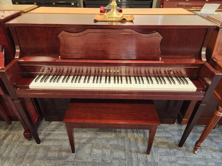 Dark wood upright piano with matching bench in a carpeted room