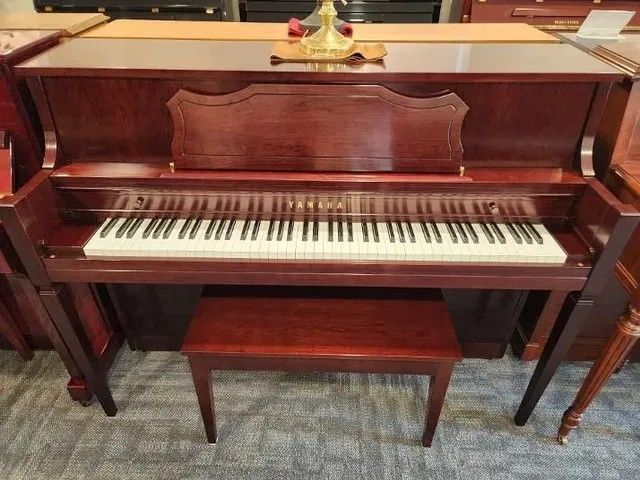 Dark wood upright piano with matching bench in a carpeted room