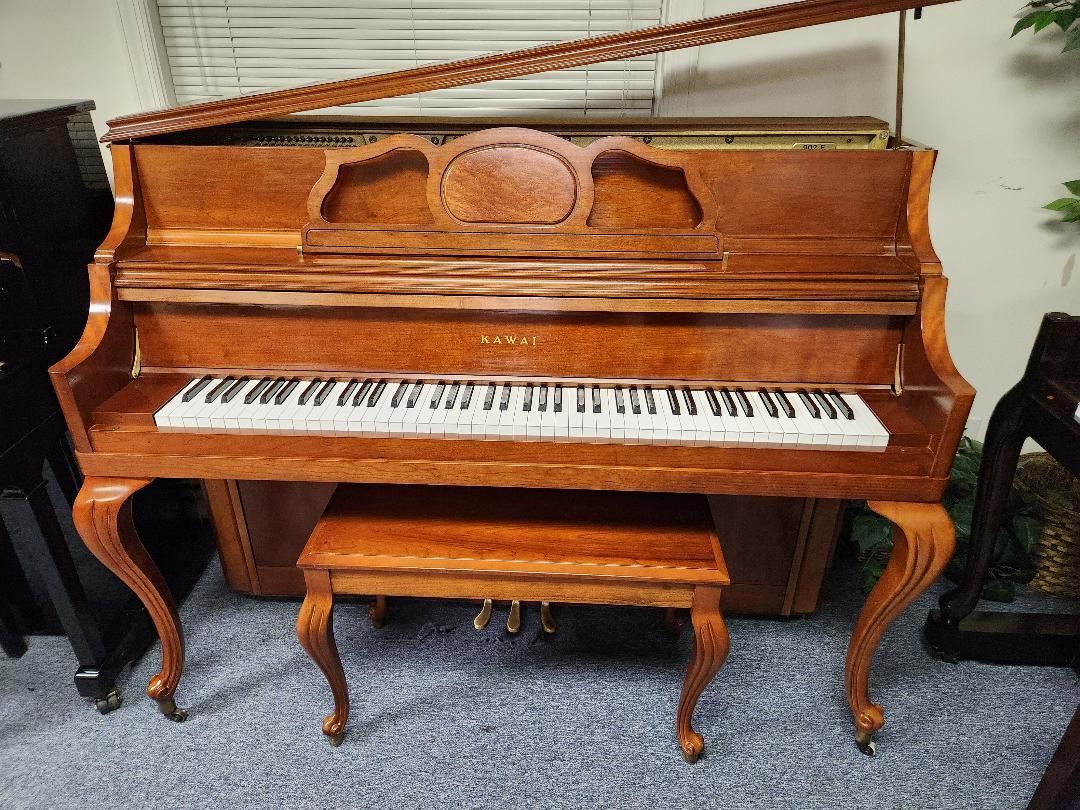 Upright wooden piano with bench; keys visible. Interior details with wood grain.