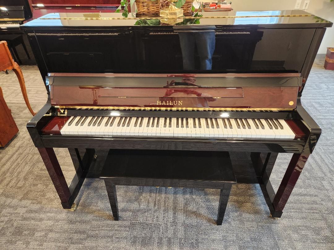 Wooden upright piano with bench; Yamaha brand. Brown wood, keys visible.