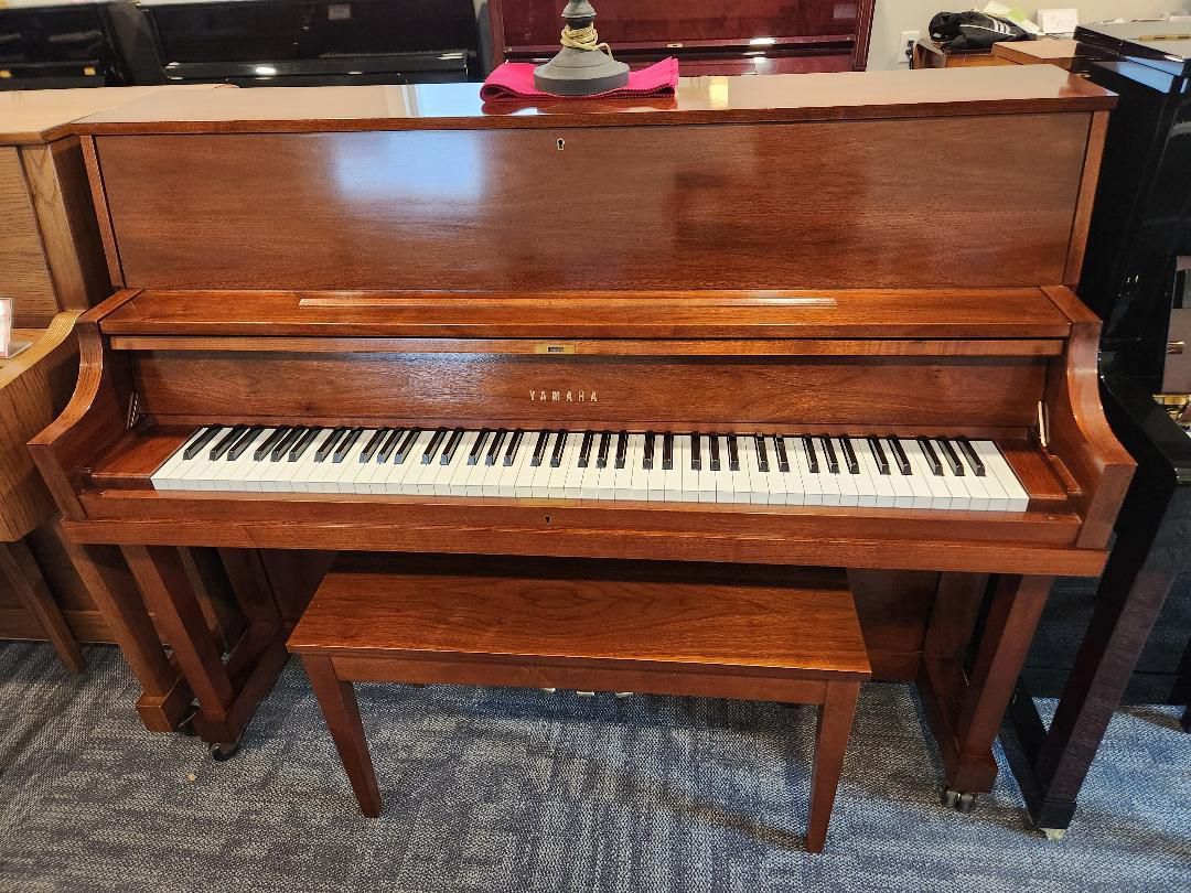 Brown Yamaha upright piano with bench in a room.