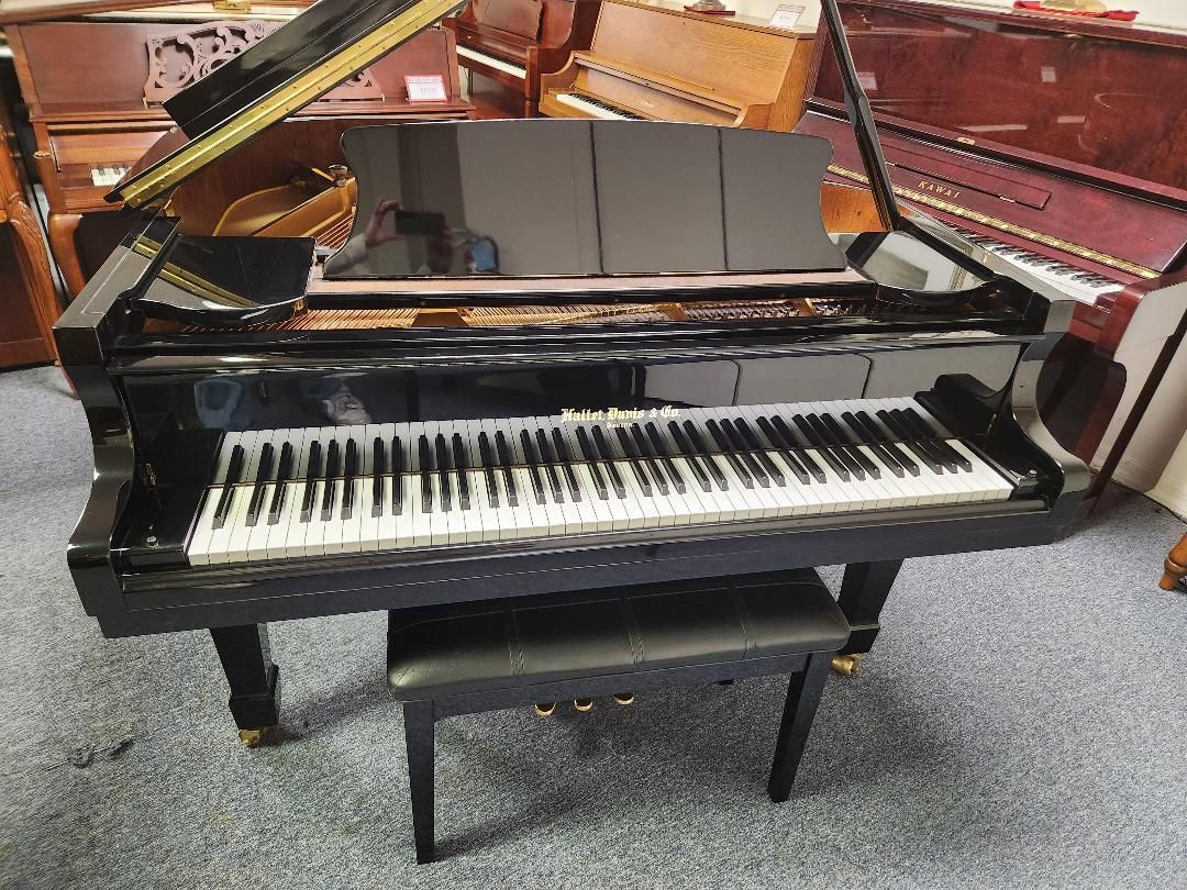 Black grand piano with open lid, keys, and matching bench.