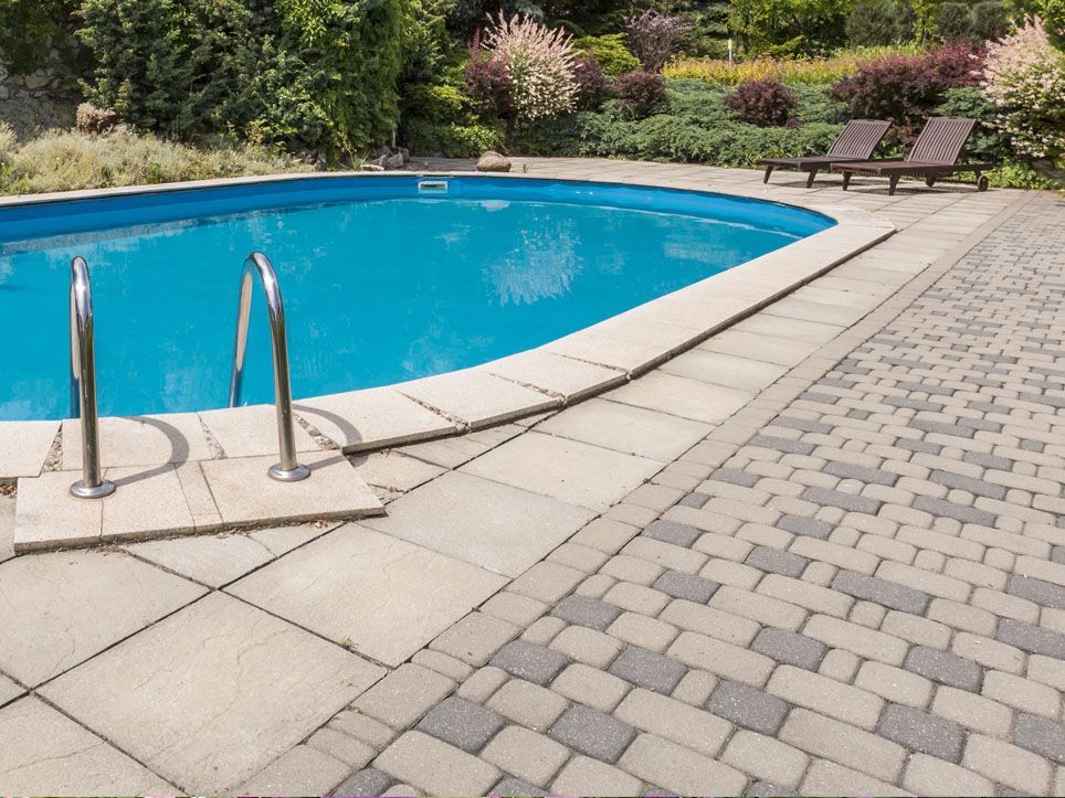 Outdoor swimming pool with blue water, stone deck, and landscaped garden seating area