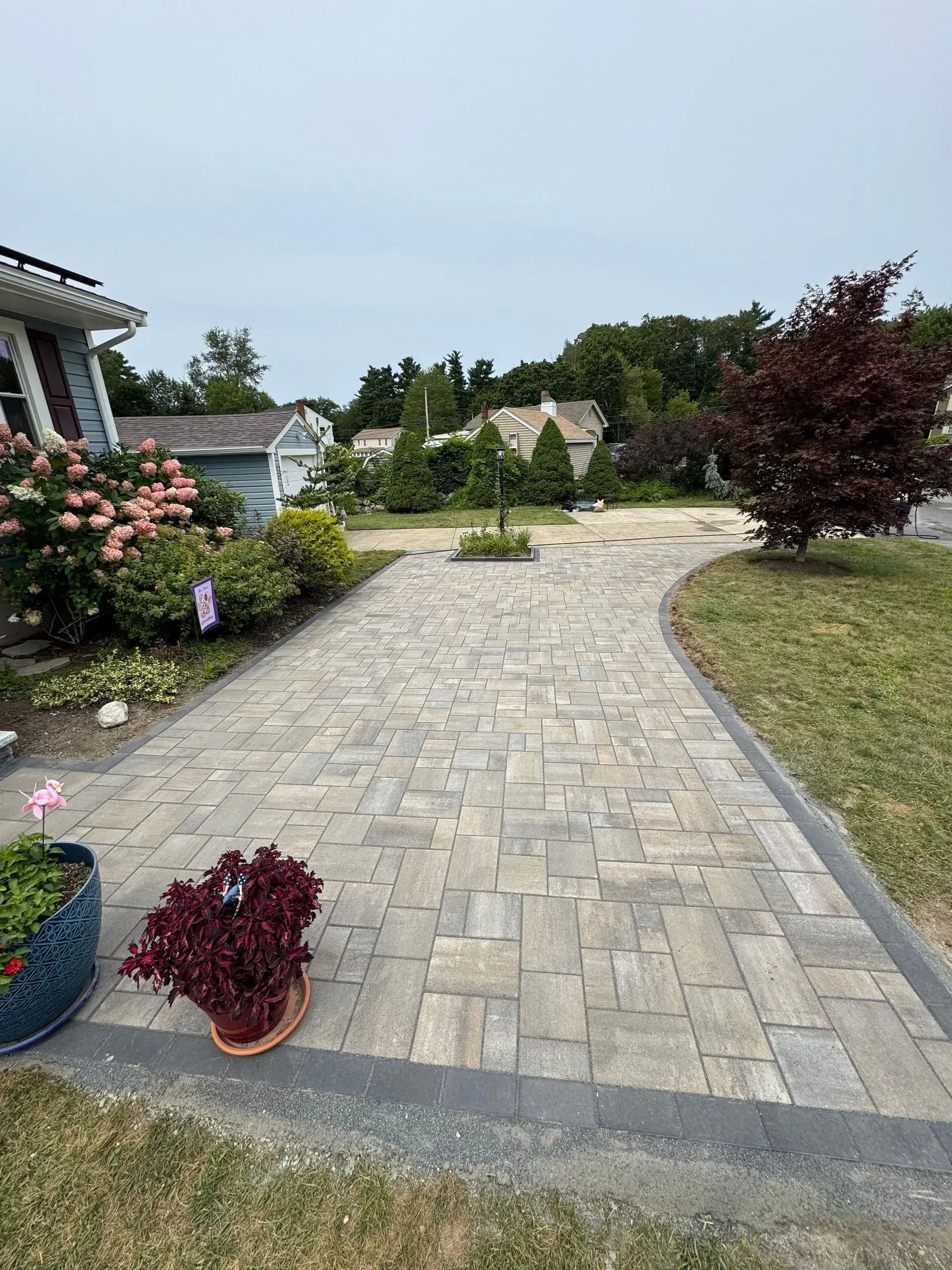 Brick paved pathway leading towards a group of small houses on a cloudy day.