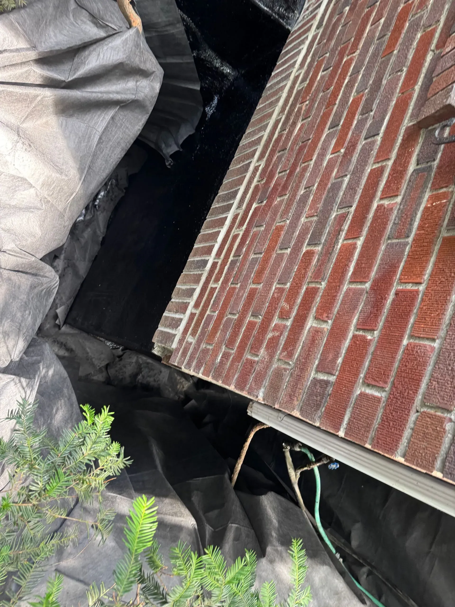 Black fabric lining a narrow gap next to a brick building.