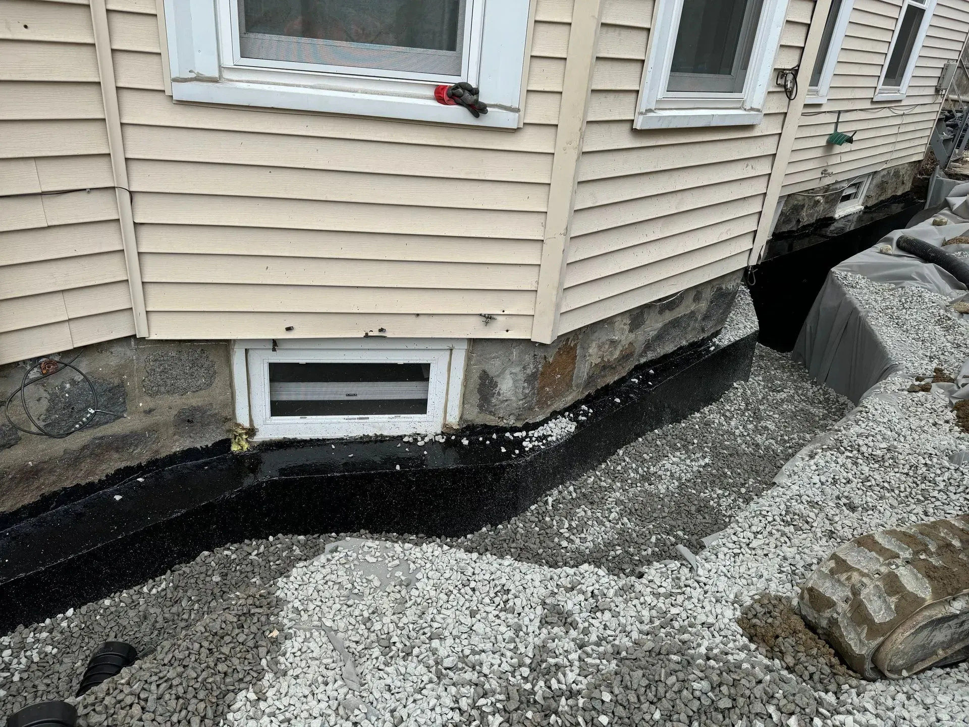 House foundation with gravel drainage, black sealant, and window.