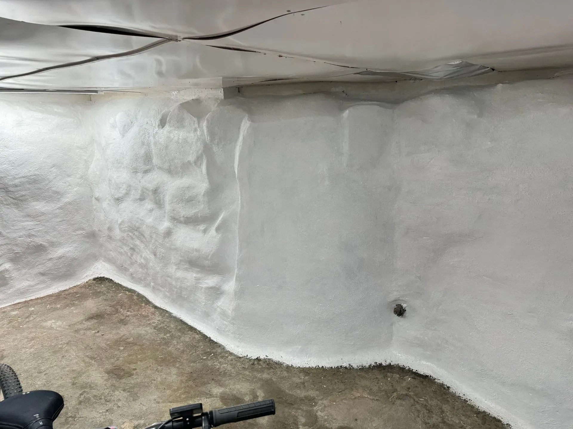 White-painted basement walls with a bicycle visible in the lower foreground. The floor is concrete.