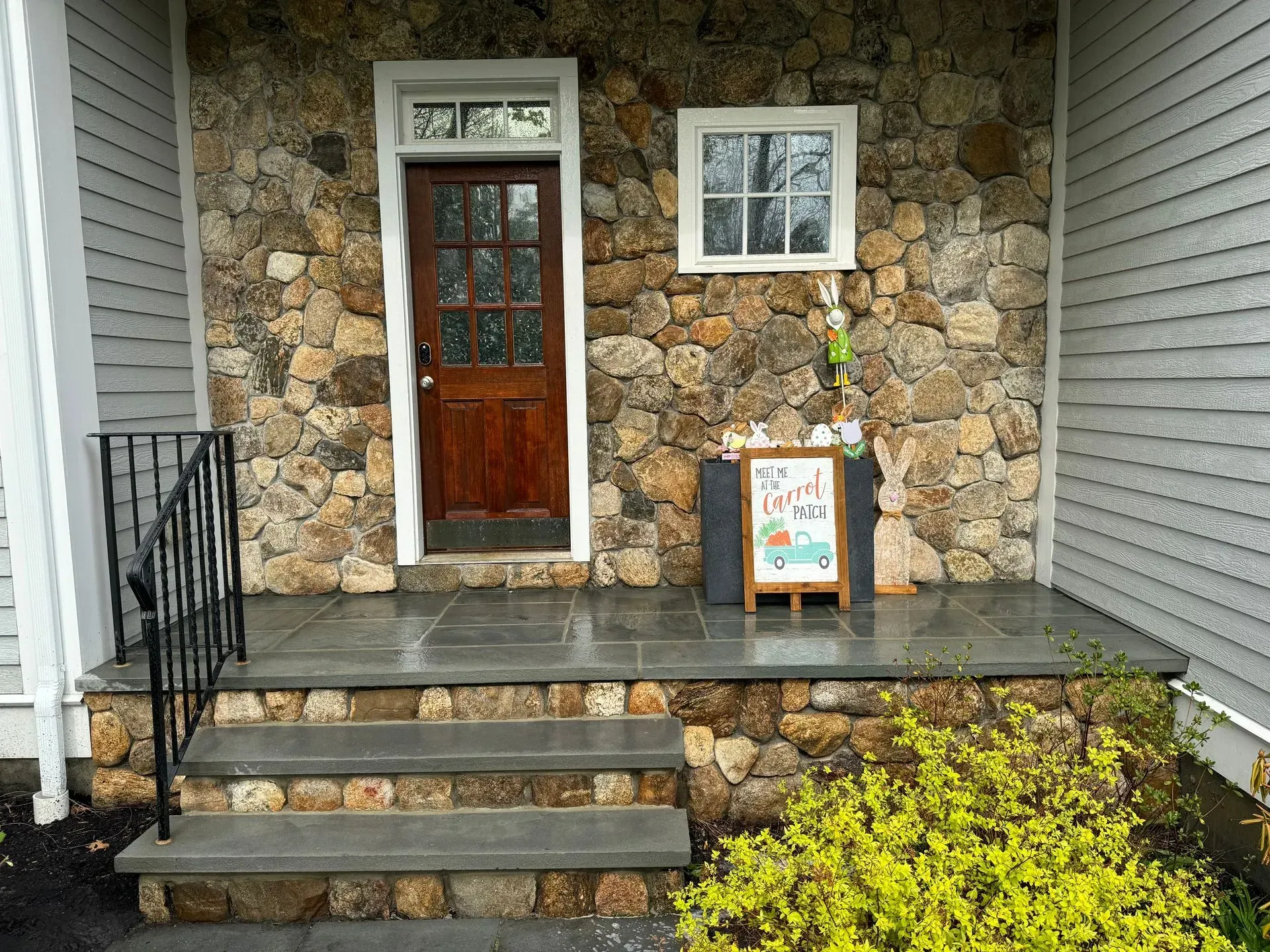 Stone building entrance with wooden door, steps, and sign.