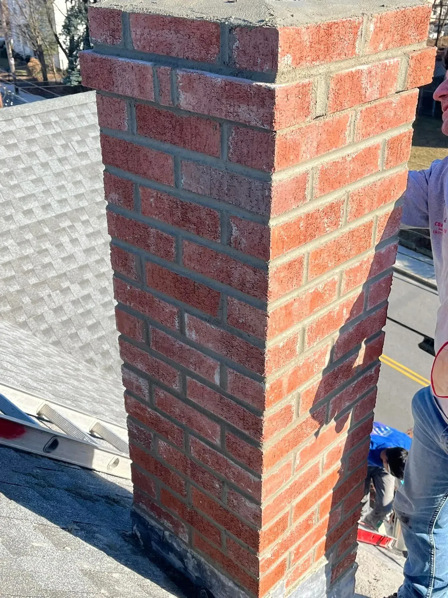Brick chimney on a rooftop; person working on the structure.