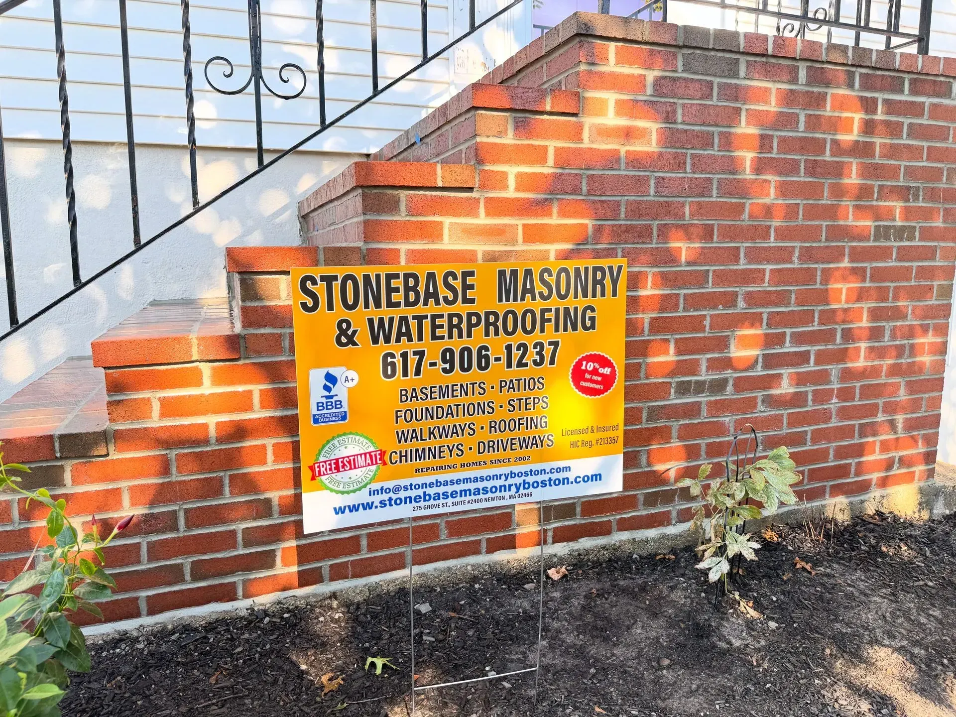 Sign for Stonebase Masonry & Waterproofing on brick steps. Phone number 617-906-1237.