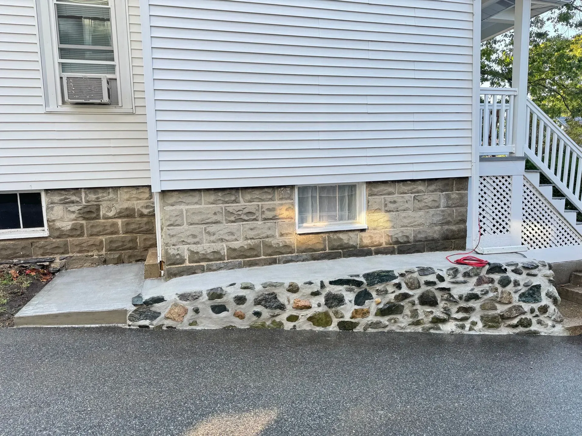 Exterior of a white house with a stone foundation and a ramp leading to the entrance.