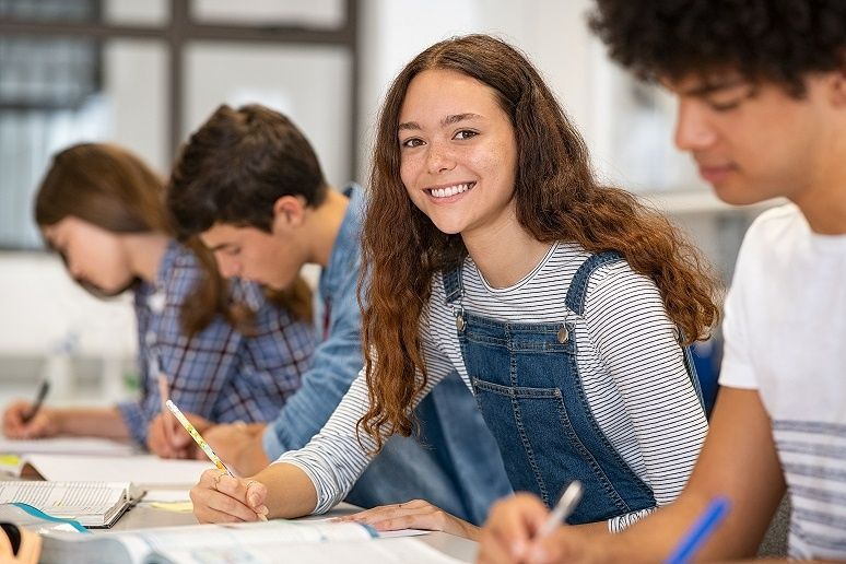 A group of young people are sitting at a table in a classroom.
