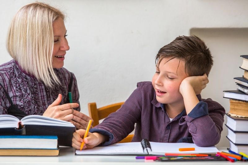 A woman is helping a young boy with his homework.
