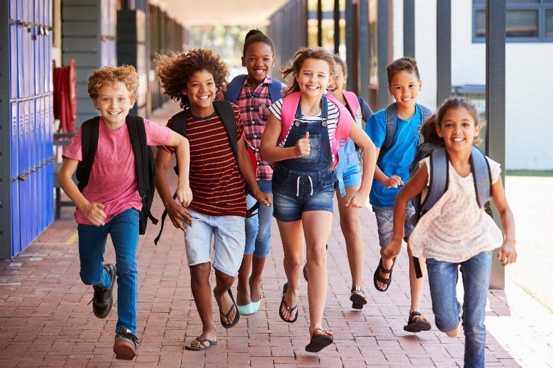 A group of children are running down a school hallway.