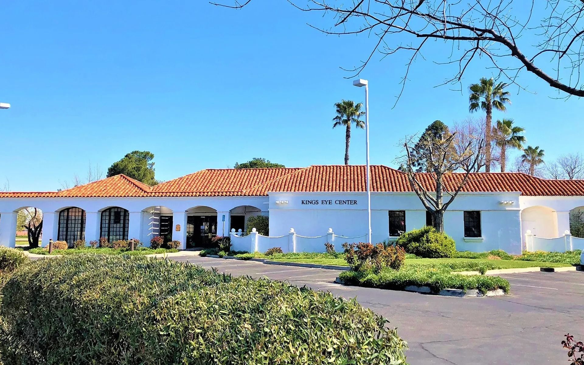 Painter in a yellow hard hat applies white paint to building exterior, contrasted against existing green wall.