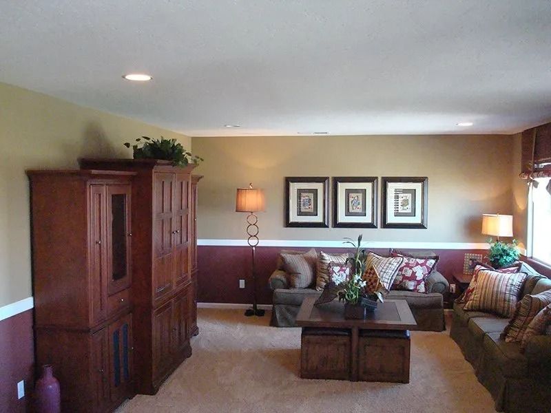 Living room with two-tone walls, dark wood entertainment center, sofa, coffee table, and framed art.