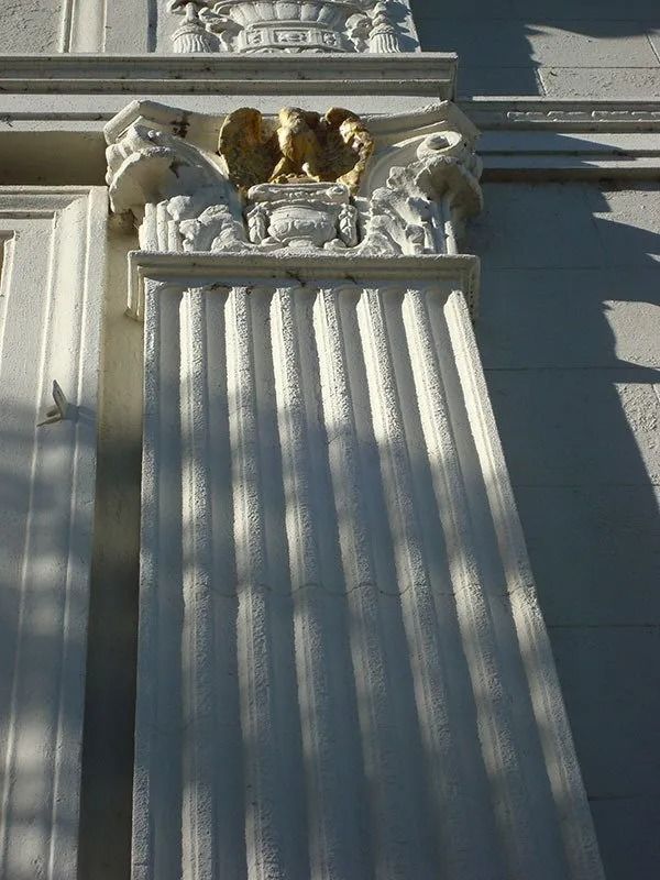 White fluted column with ornate capital featuring golden eagle statues.