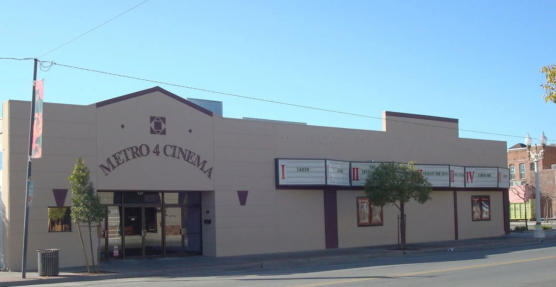 Metro 4 Cinema exterior, tan building with marquee posters under a blue sky.