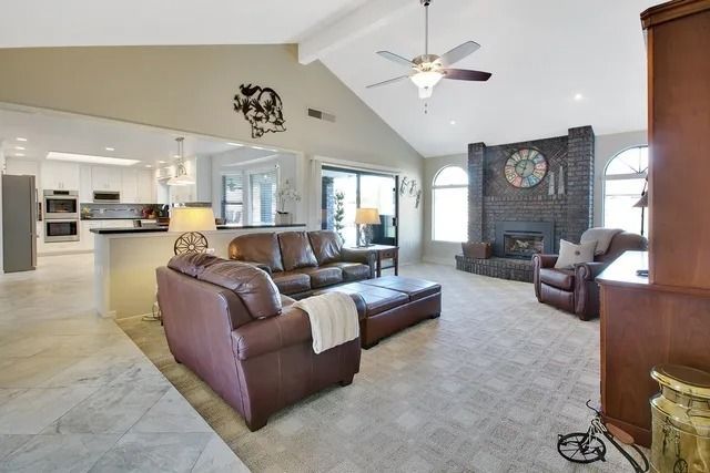 Living room with leather furniture, fireplace, and open kitchen.