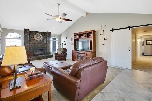 Living room with brick fireplace, leather furniture, TV, and a sliding barn door.