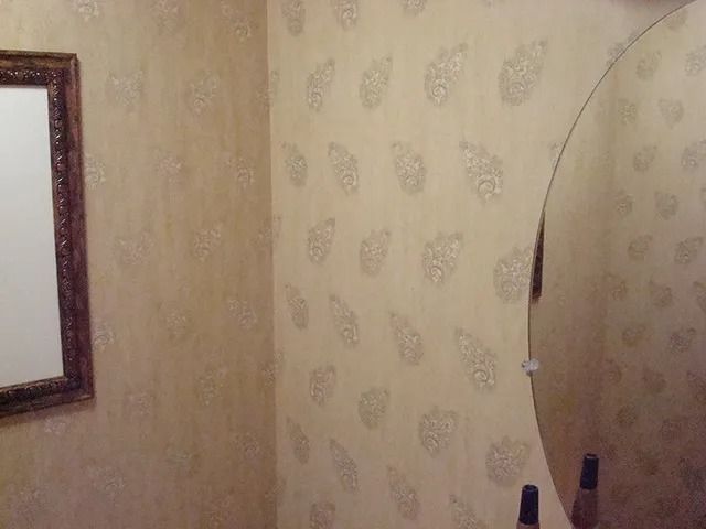 Corner of a room with paisley wallpaper, mirror, and framed artwork.