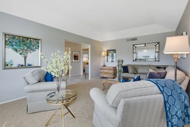 Living room with light gray walls, white furniture, blue accents, and a large mirror.