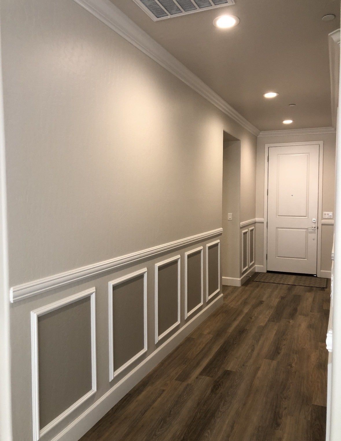 Long hallway with light gray walls, white trim, and dark wood flooring.