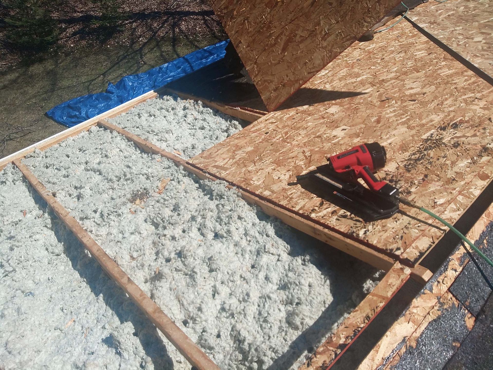 Rooftop construction with wood frame, insulation, and nail gun.