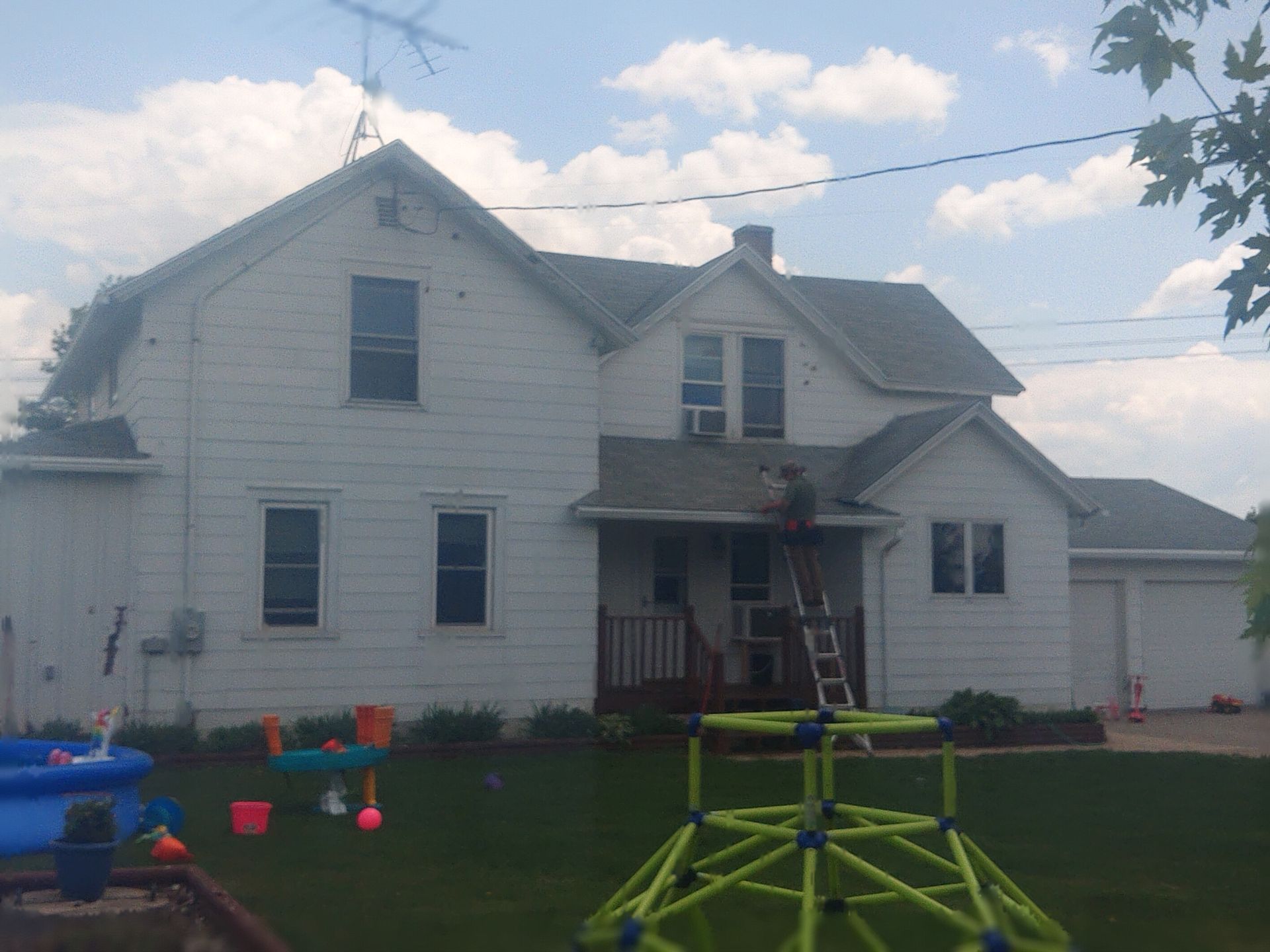 White two-story house with green lawn; children's toys in the foreground.