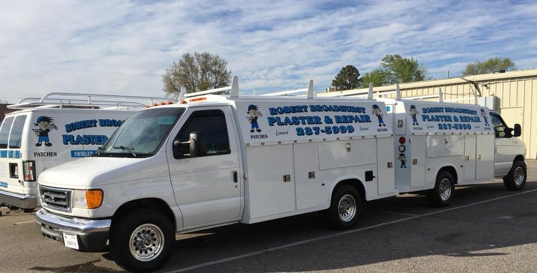 White work vans with company logo parked outdoors.