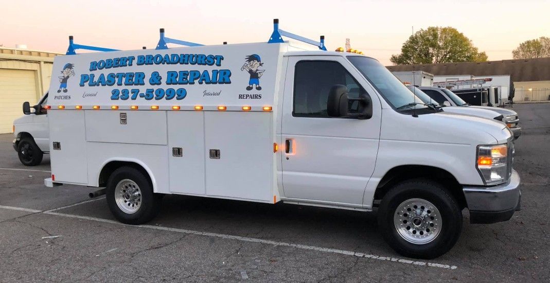 White work van with side storage, ladder rack, logo: 