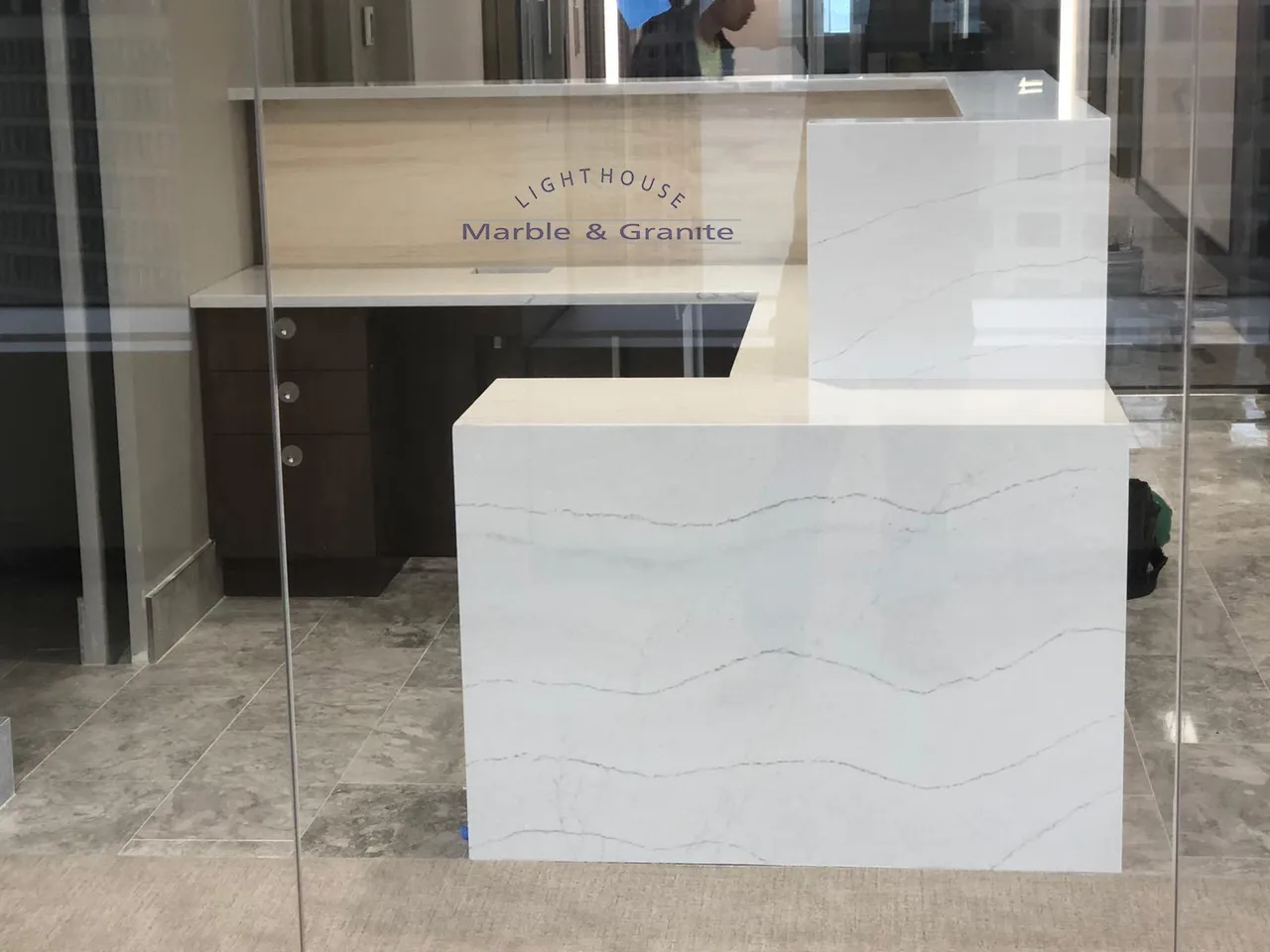 a white counter is behind a glass wall in an office