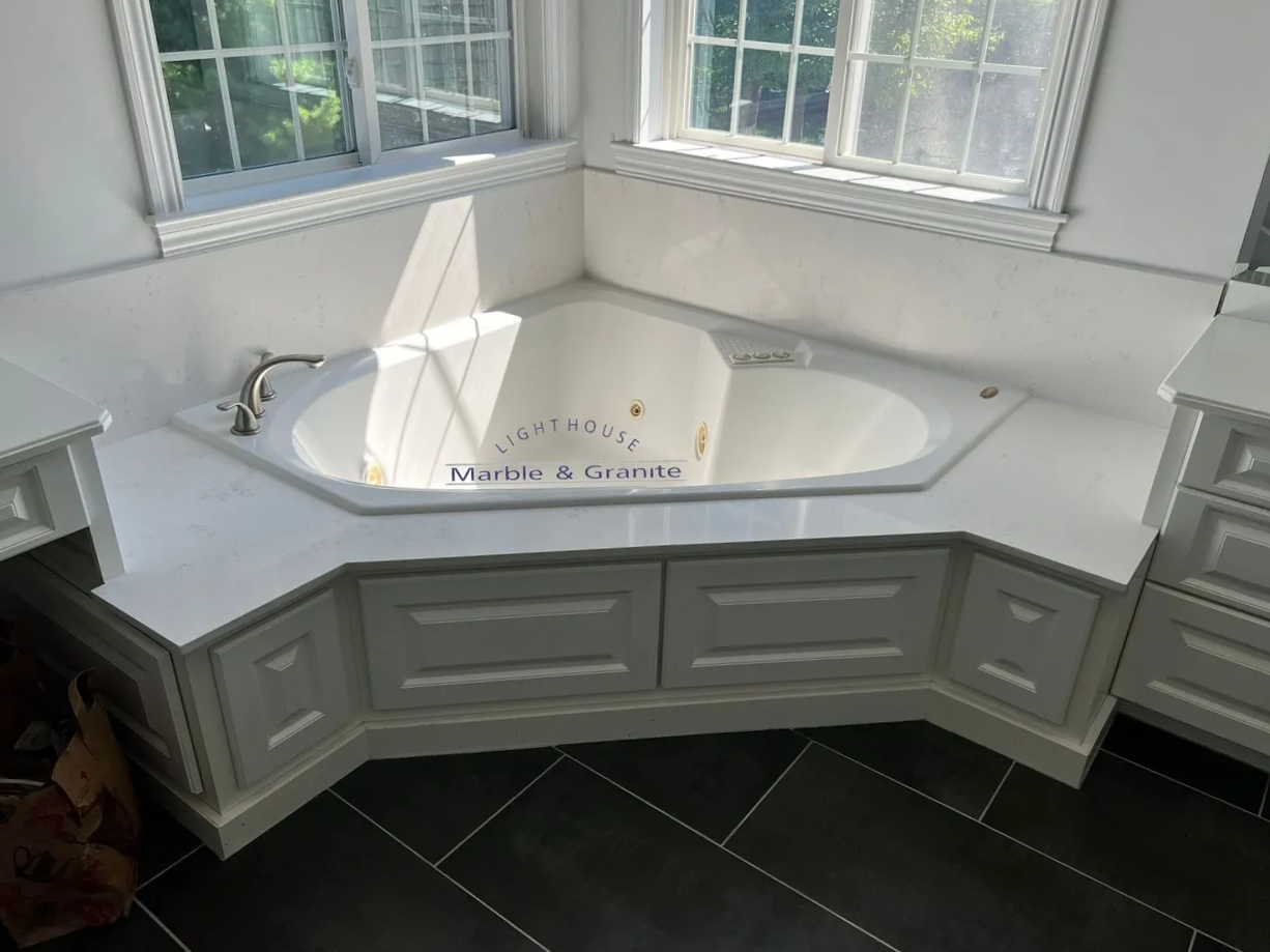 a bathtub in a bathroom with white cabinets and a window