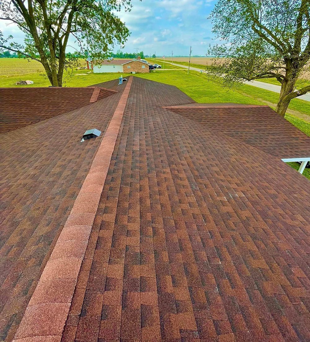 A roof with a lot of shingles on it and trees in the background