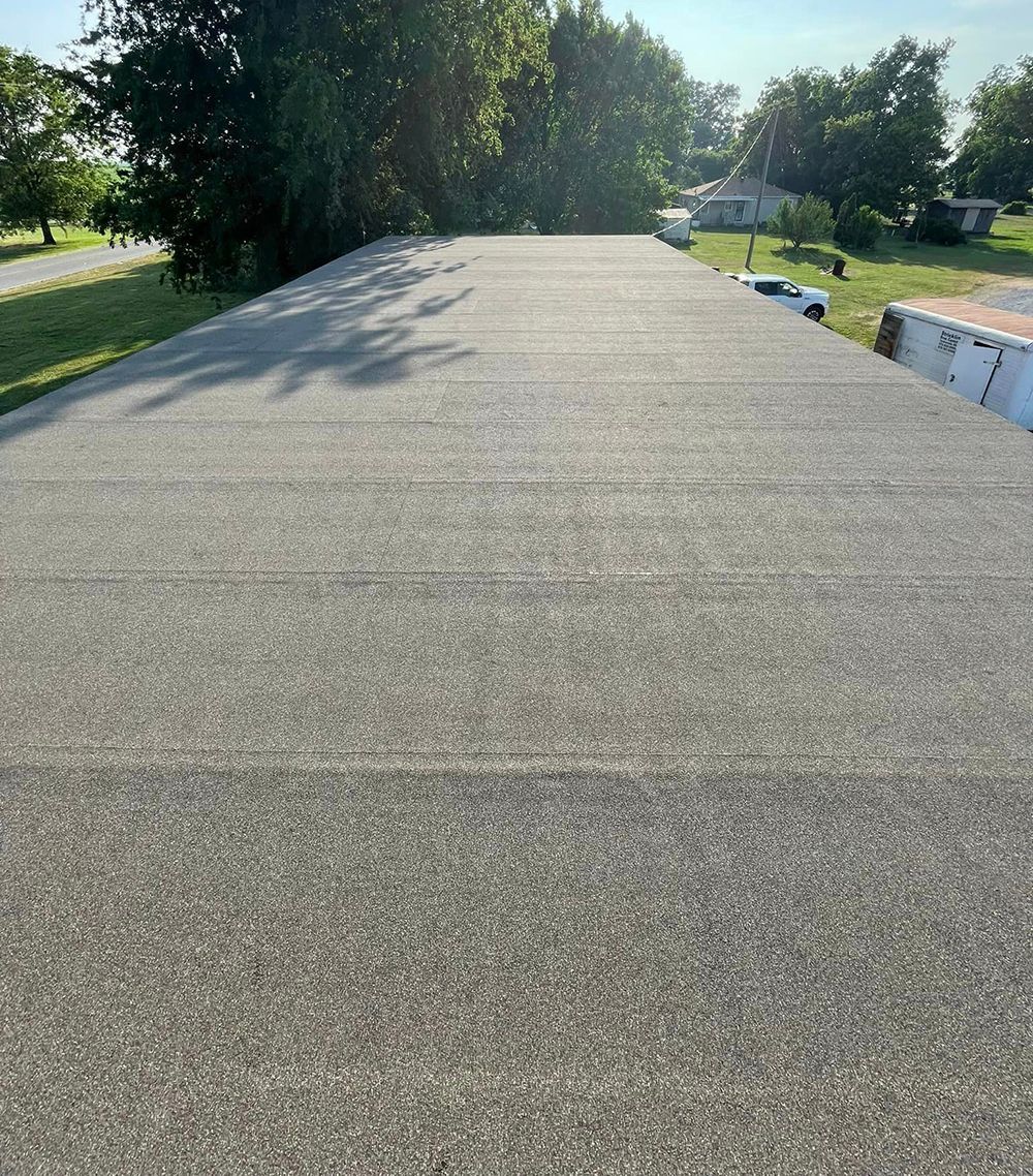 A gray flat roof with trees in the background