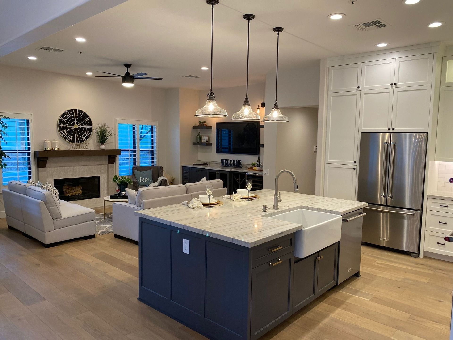 Open-concept kitchen and living room with island, fireplace, and stainless steel appliances.