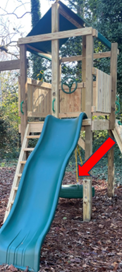 A wooden playset with green slide and tire swing