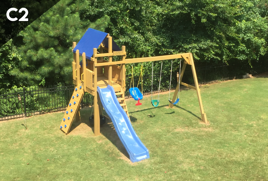 A wooden playground set with a blue slide and swings in a backyard.